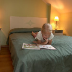 Koidulapark hotellin perhehuone. Lapsi lukee kirjaa parivuoteella.