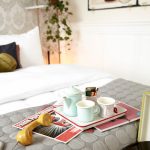 Teekannu ja teemukit tarjottimella parivuoteen päällä