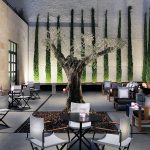 Hotellin terassia kuvattuna öiseen aikaan, upea valaistus puissa ja seinän kasveissa