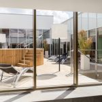 Näkymä ikkunasta allasosaston ulkoterassin altaalle ja oleskelualueelle