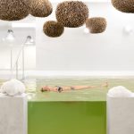 Nainen kelluu sammalenvihreässä kuolleenmeren altaassa