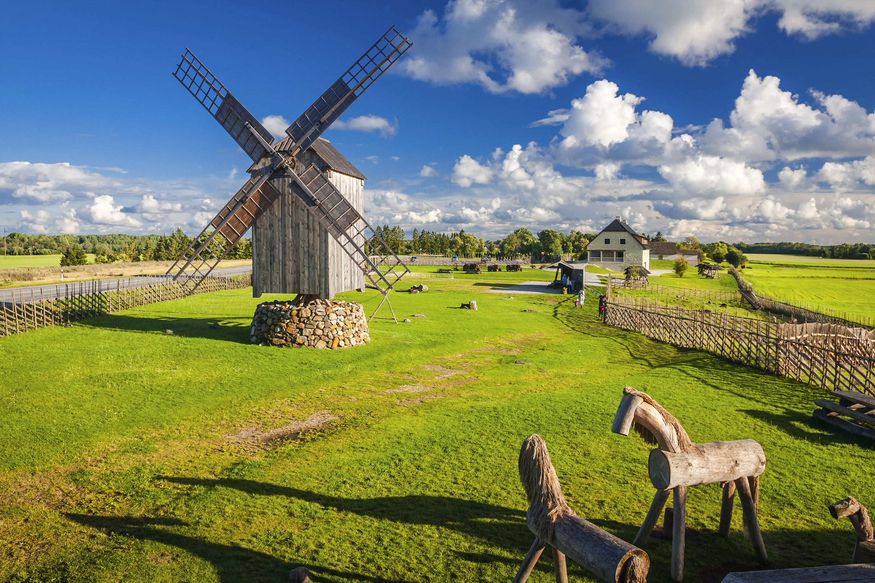 Puinen tuulimylly ja puuhevoset kirkkaana kesäpäivänä.