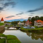 Piispanlinnan torni, joki, silta ja saari vanhoine rakennuksineen auringon noustessa.