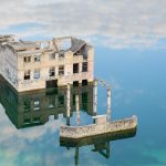 Rummun hylätty rakennus keskellä kirkasvetistä järveä