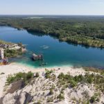 Rummun hylätty louhosalue kuvattuna ylhäältä. Kirkasvetinen järvi, jonka pohjalla näkyy rakennuksia.