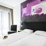 Comfort Hotel LT:n standard huone, jonka sängyn päädyn seinää koristaa värikäs maalaus discosta