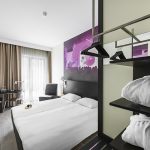 Comfort Hotel LT:n standard huone, jonka sängyn päädyn seinää koristaa värikäs maalaus