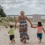 Isoäiti ja lapsenlapset juoksevat rantahietikolla käsi kädessä