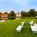 Valkoisia penkkejä puistossa lammen rannalla.