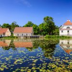 Vihulan kartanorakennuksia lammen takana, lammen pinnalla lumpeenlehtiä.