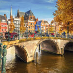 Kivinen silta kanaalin yllä syksyisessä Amsterdamissa. Sillalla pyöriä parkissa.