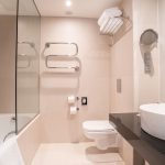 Standard huoneen kylpyhuoneessa on amme ja vaaleat laatat