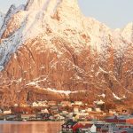 Rakennuksia tunturien edessä meren rannalla