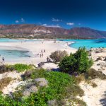 Turkoosin sinistä vettä, rannalla olijoita vuoristoa ja valkoista hiekkaa