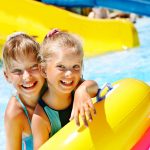 Kaksi tyttöä uimarenkaiden kanssa vesipuistossa