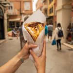 Gyros kadulla kävelevän kädessä