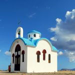 Pieni sinivalkoinen kirkko autiolla hiekkakentällä