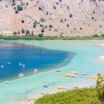 Maisema ylhäältä järvelle, ihmisiä uimassa ja veneilemässä.