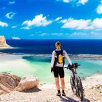 Henkilö seisoo pitäen kiinni maastopyörästä ja ihailee merimaisemaa.