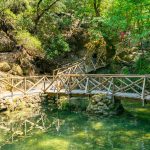 Puinen silta kirkkaan lammen yllä vehreässä Perhoslaaksossa.