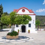 Puuston ympäröimällä tasanteella valkoinen pieni luostari.