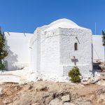 Vanhan valkoisen luostarin julkisivu, johon aseteltu puinen risti.