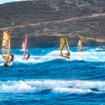 Purjelautailijoita etenemässä aallokossa.