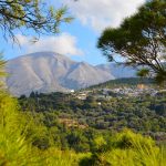 Näkymä metsästä kohti kylää ja vuoria.