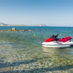 Punavalkoinen vesiskootteri matalassa rantavedessä.