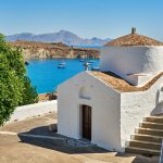 Pieni, valkoinen kirkkorakennus veden äärellä.