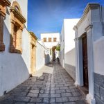 Kapea kuja valkoisten rakennusten välissä.