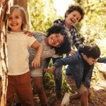 Neljä lasta hassuttelee metsäisessä ympäristössä.