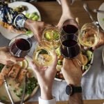 Ystävykset kohottavat viinilaseja ruokien yllä.