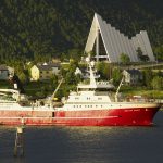 Kalastusalus Tromssan edustalla, taustalla näkyy Jäämerenkatedraali.