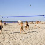 Ihmisiä pelaamassa rantalentopalloa aurinkoisena päivänä.