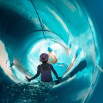 Lapset laskevat vesiliukumäen putkessa peräkkäin.