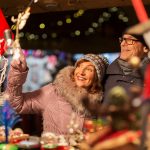 Hymyilevä pariskunta katselee jouluista näyteikkunaa.