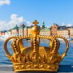 Kruunukoriste sillanreunalla lähikuvassa, taustalla kaupunki.