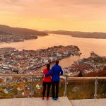 Pariskunta katsomassa Bergenin kaupunkia auringonlaskun aikaan Floyen vuorelta