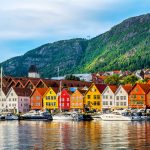 Venesatama ja värikkäitä puutaloja mereltä päin kuvattuna.