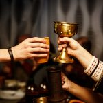 Keskiaikaisiin asuihin pukeutuneet henkilöt nostavat maljoja.