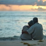 Pari istuu ja halaa rannalla