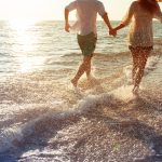 Pariskunta juoksee rantavedessä