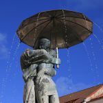 Suutelevat opiskelijat-patsas sinistä taivasta vasten