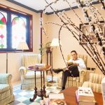 Mies lukee nojatuolissa lehteä