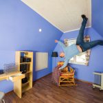 Mies seisoo ylösalaisin olevan huoneen katossa ja kurkottelee käsillään.