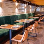 Vihreä sohva ja ruskeita tuoleja ravintolassa