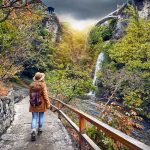 Nainen kävelee kasvitieteellisessä puutahassa.