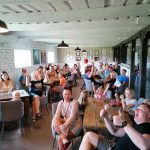 Iloisia ihmisiä pöytien ympärillä