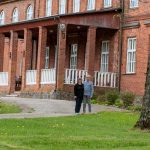 Mies ja nainen punatiilisen kartanon edustalla